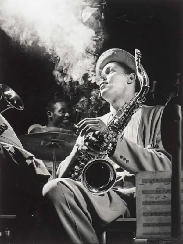 A saxophonist playing in a smoky club, black and white